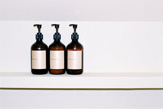 Set of bottles with shampoo, conditioner and body soap on the shelf.