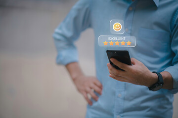 Businessman using smartphone to give five-star positive review with smiley face icon, Customers give 5-star reviews,symbolizing excellent customer feedback, and user satisfaction in digital service.
