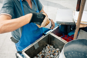 Street Vendor Serving Roasted Chestnuts in a Busy Market
