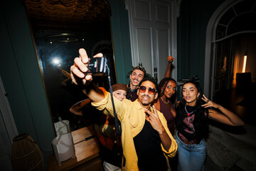 Diverse friends capturing selfie during home party