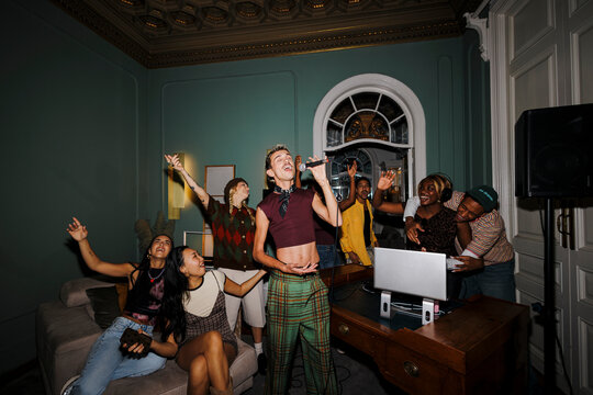 Friends singing karaoke at home having fun party