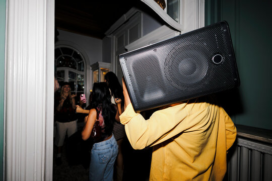 Person carrying speaker on shoulder at house party