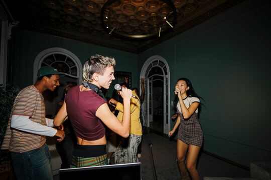 Diverse friends enjoying home party karaoke together