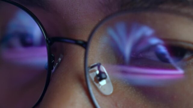 A person wearing glasses works on a laptop, with a glowing digital open book reflected in the lens. Highlights e-learning, digital reading, online education, knowledge access, and modern technology.