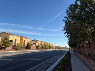 uburban Open Road Las Vegas: Empty residential street between housing complexes under a blue sky.