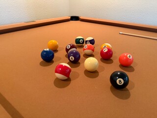 Billiards Table 9-Ball Game: Pool table with beige felt cloth featuring multiple balls arranged for a game.