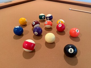 Billiards Table 9-Ball Game: Pool table with beige felt cloth featuring multiple balls arranged for a game.