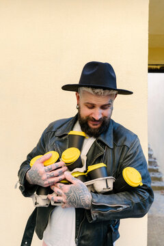 A man is trying to hold onto several disposable cups for drinks