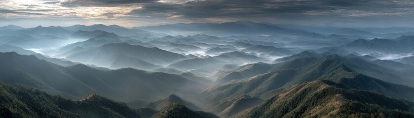Fototapeta premium A misty mountain range beneath cloudy sky concept. Breathtaking mountain view with misty valleys and sky.