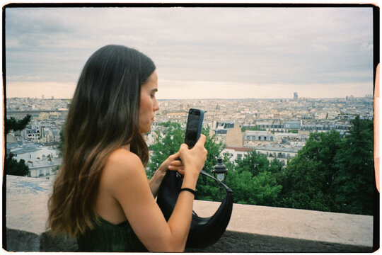 Female tourist using a smartphone to take photos of the city of Paris