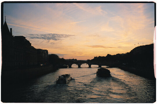 Analog cityscape with boats sailing on the Seine River during sunset