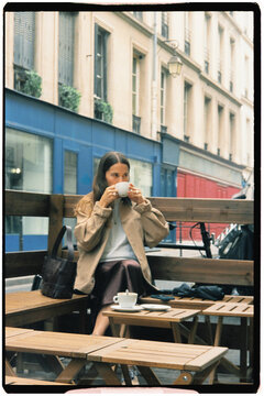 Medium film shot of a traveler sitting outdoors at a Parisian cafe