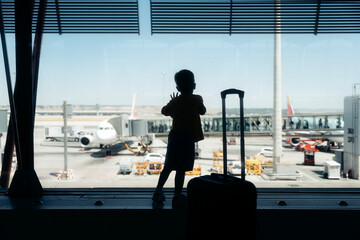 Boy silhouette waiting by airport window for journey