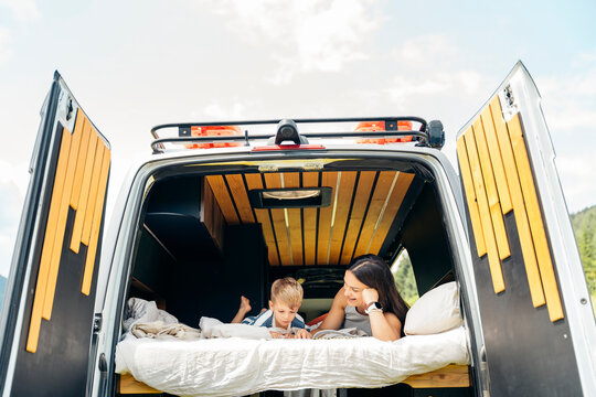 Mother and son reading book enjoying van life