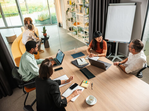 Diverse Team Meeting in Modern Office With Laptops and Notebooks