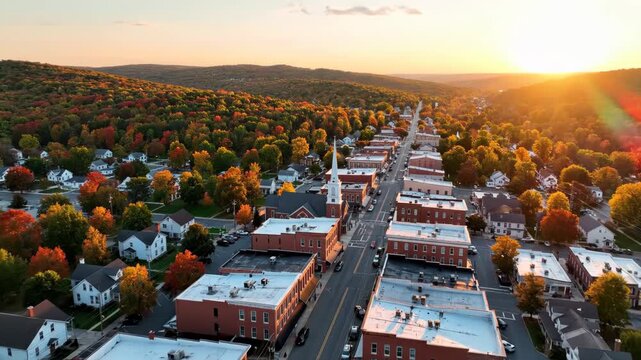 Aerial view of a small town main street lined with brick buildings during a vibrant autumn sunset vector illustration