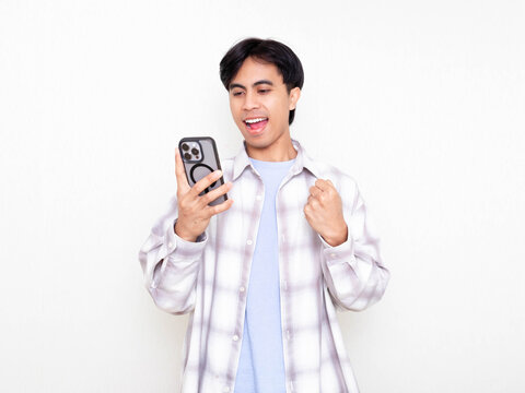 Young man celebrating while checking his smartphone, showing excitement about digital business results on a clean white background.