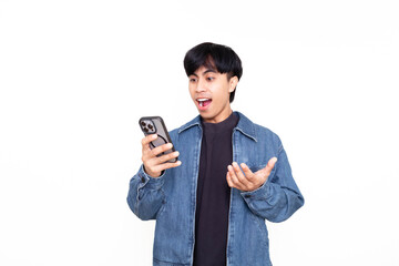 Happy young Asian man holding a smartphone with open mouth and raised hands, showing an excited surprised reaction on a plain background, ideal for advertising and digital promotions.