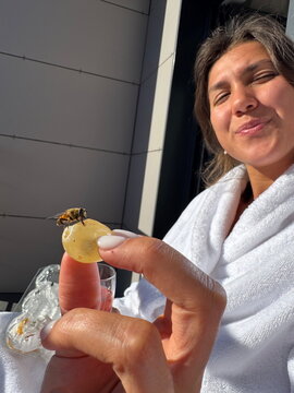 Bee on grape with woman smiling in morning light