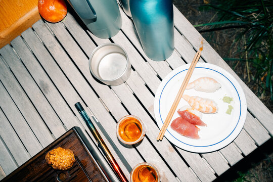 Fresh Sushi Served Outdoors With Drinks on a Wooden Table