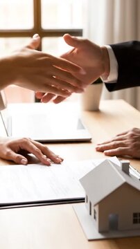 Signing papers with house model, window in background