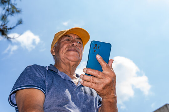 Mexican senior man using smartphone connecting outdoors