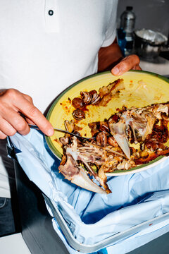 a man empties chicken and snails remains into the bin