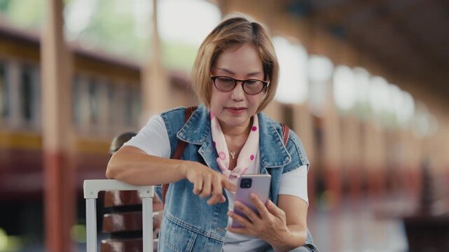 Mature woman using smartphone while waiting at train station