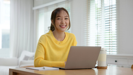 Remote work from home office desk asia people digital nomad young gen z teen female smile look at camera sit self relax tech talent career life balance happy hybrid stock trader job study learn online