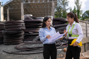 Two women engineers reviewing building plans at a job site with rebar
