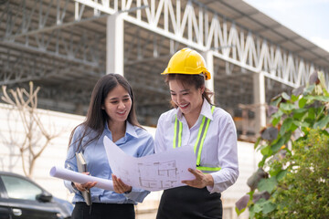 Women engineers reviewing blueprint at construction site
