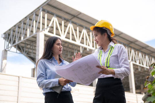 Women engineers discussing blueprint at construction site