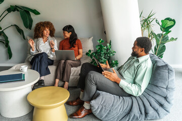 Casual Business Meeting With Co-Workers on Sofa Using Laptops 