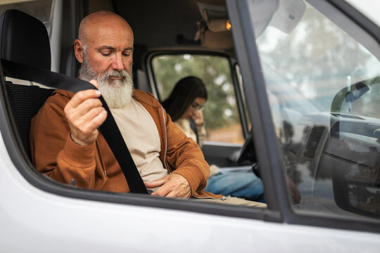 Father and adult daughter fastening seatbelts in campervan