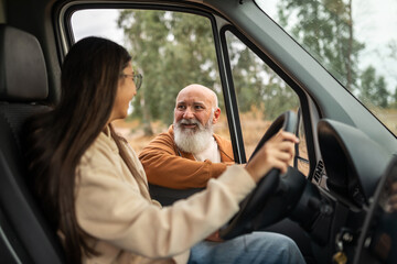 Father giving driving instructions to young woman in campervan
