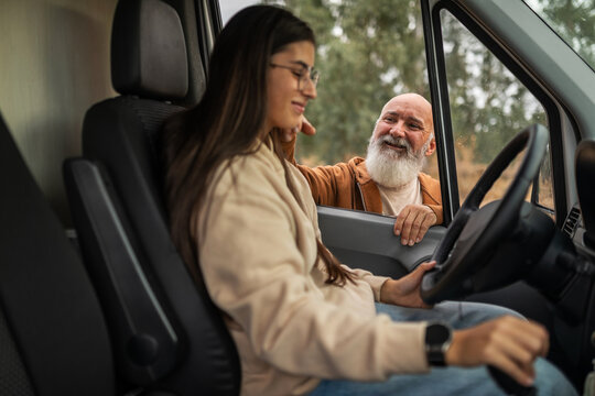 Father giving driving instructions to young woman in campervan