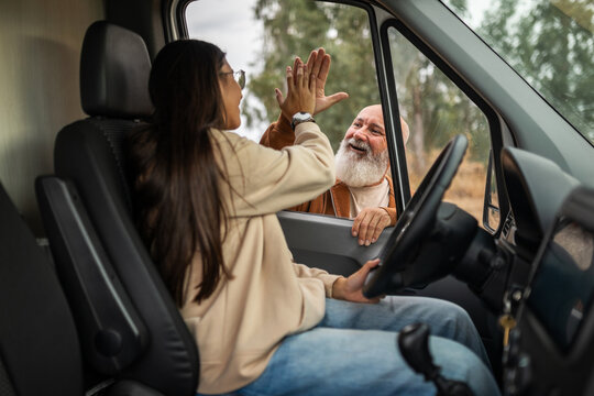 Father and daughter high-fiving beside campervan