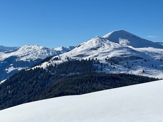 Obraz premium Beautiful sunlit and snow-capped alpine peaks above the Swiss village and winter resort of St. Antönien (St. Antoenien) - Canton of Grisons, Switzerland (Kanton Graubünden, Schweiz)