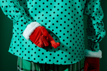 red velvet-gloved hand crossing fingers behind a man in green clothes