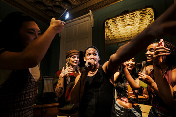 Diverse friends enjoying karaoke singing at party