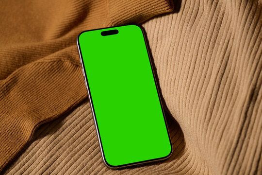 Smartphone with green screen on a cozy fabric background