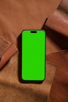 Smartphone with green screen on leather background