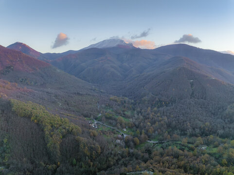 Aerial view of rolling hills and valleys blanketed with trees under a soft, pastel sky, Volturara Irpina, Campania, Italy.