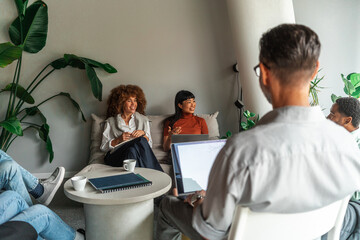 Casual Team Meeting In Modern Lounge With Laptops and Coffee