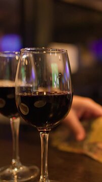 Hand Collects Scratch Cards Beside Red Wine in Bar