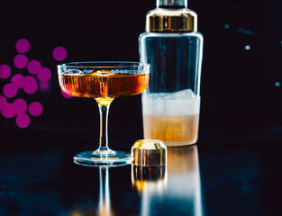 Cocktail in a glass with golden shaker and vibrant background