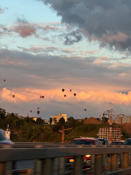 Hot air balloons above city highway at sunset