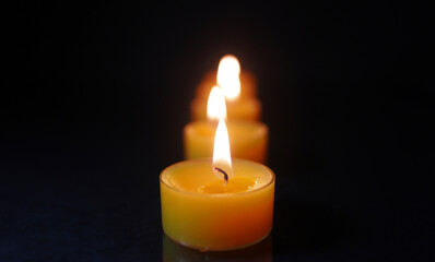 Tealight Candle Burning in Front with Soft Bokeh Flames Behind  Single Candle Flame in Focus with Blurred Candles in Background