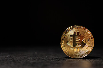 Gold Bitcoin Coin Standing on Dark Surface with Copy Space Shiny Bitcoin Token on Black Background in Dramatic Light