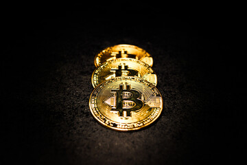 Stack of Gold Bitcoin Coins Illuminated on Dark Background Shiny Bitcoin Tokens Arranged in Row Under Dramatic Light